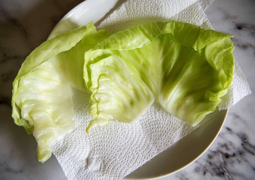 Blanched cabbage leaves lay on a paper towel for the cabbage rolls recipe