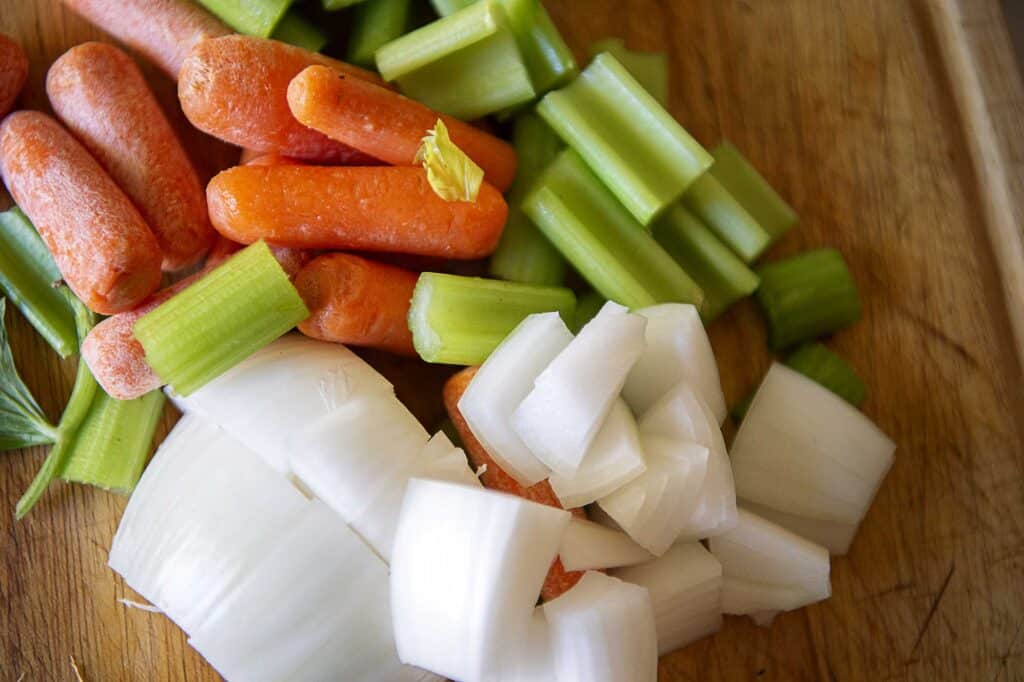 celery, onion, and carrots on a cutting board