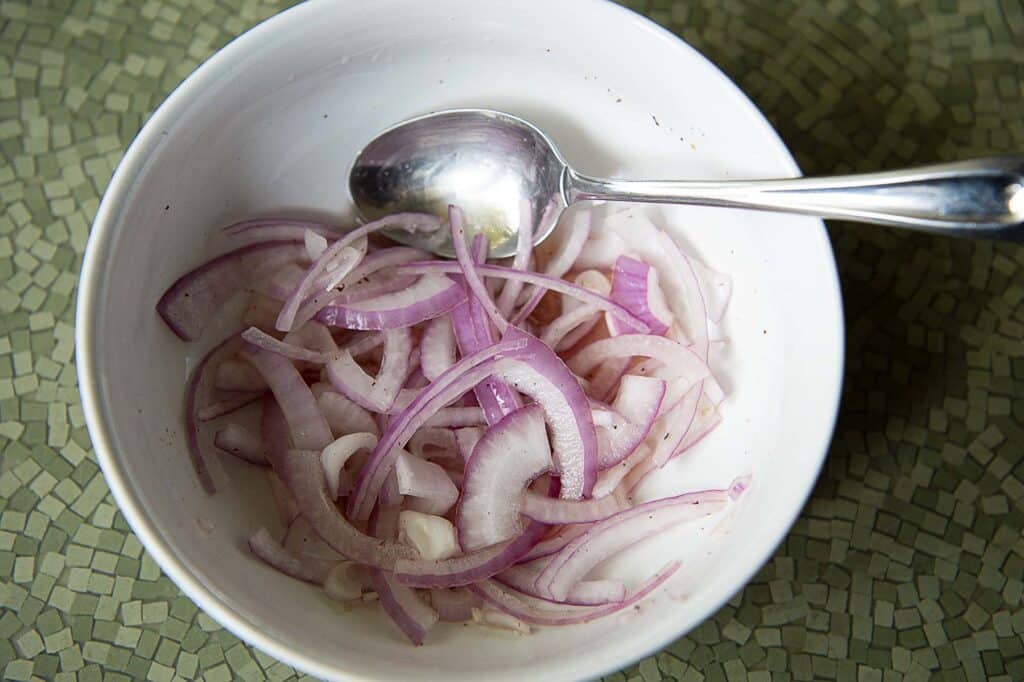 pickled red onions in a white bowl with a spoon