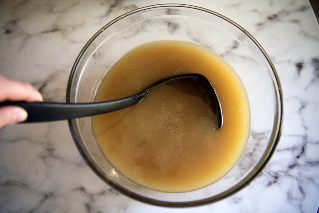 Homemade Chicken stock in a large bowl with a laddle