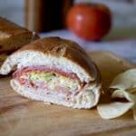 a grinder sandwich split in half next to potato chips.