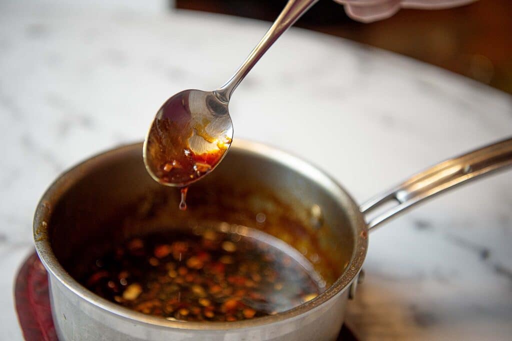 A dark sweet soy glaze drips off the spoon.