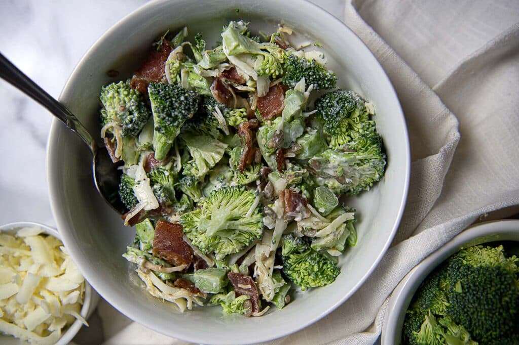 Chicken Salad Chick Broccoli Salad Recipe in a white bowl with a beautiful backdrop.
