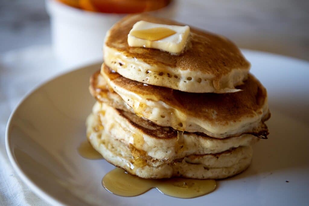 A stack of pancakes with butter and maple syrup