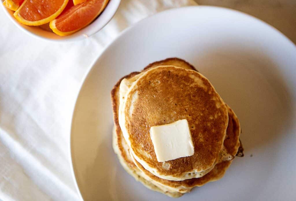 A stack of pancakes and sliced oranges