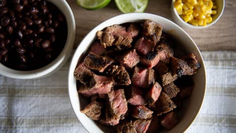 chipotle steak next to corn, beans, and limes.