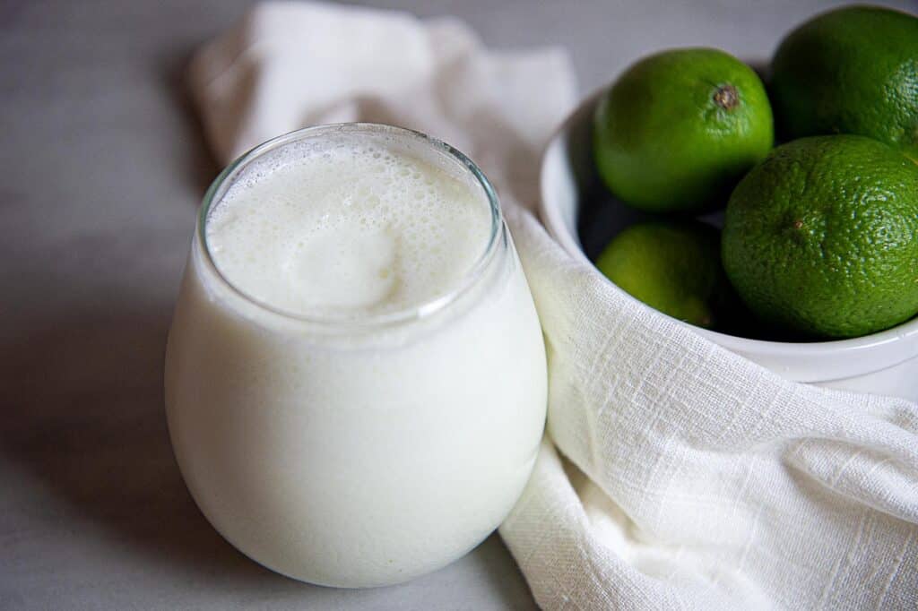 a cold glass of limonada next to limes