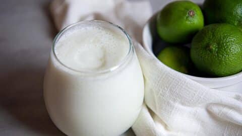 a cold glass of limonada next to limes