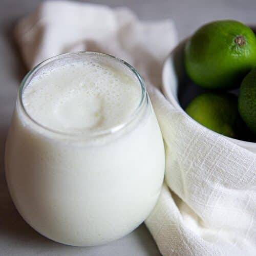 a cold glass of limonada next to limes