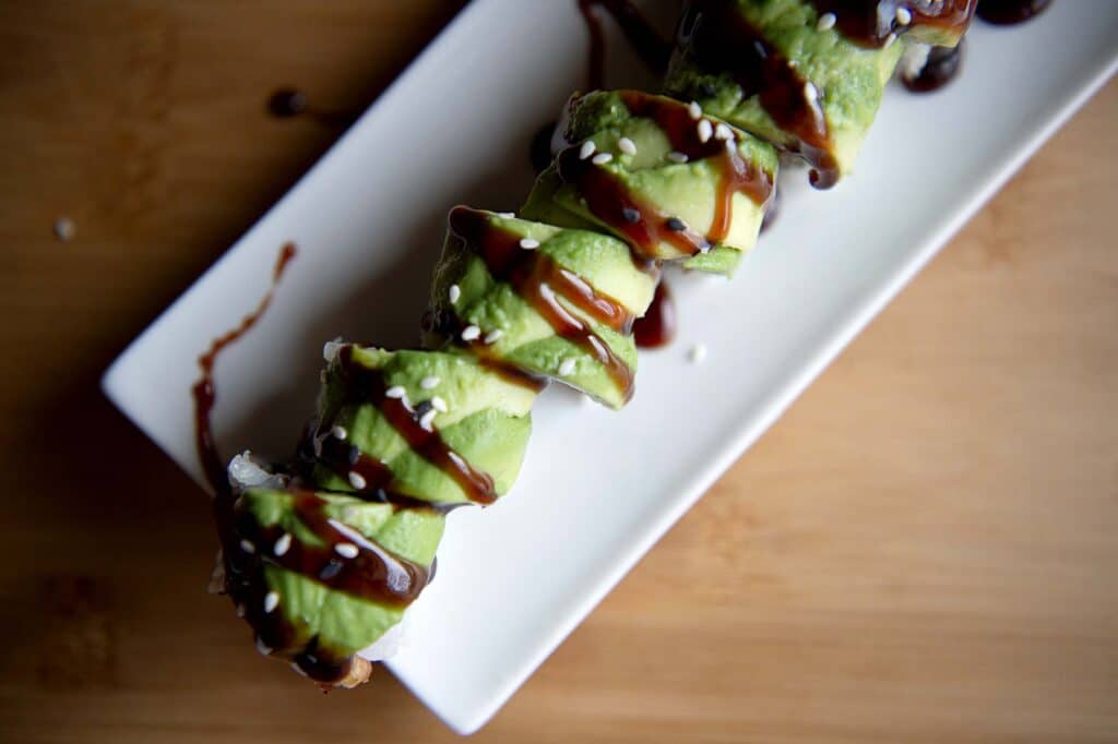 An up-close photo of a caterpillar roll with eel sauce drizzled on top of it.