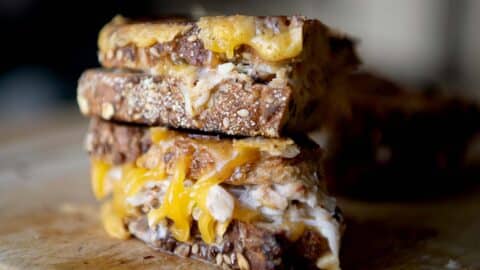 A close up shot of a crab melt sandwich on a cutting board.