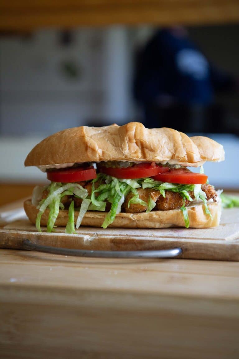 A shrimp po boy sitting on a wooden cutting board.