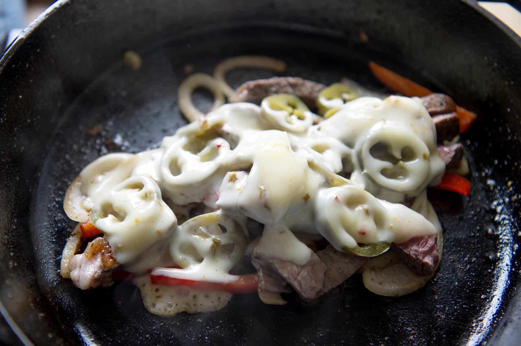 The ingredients of a lamb grinder covered in a white cheese.