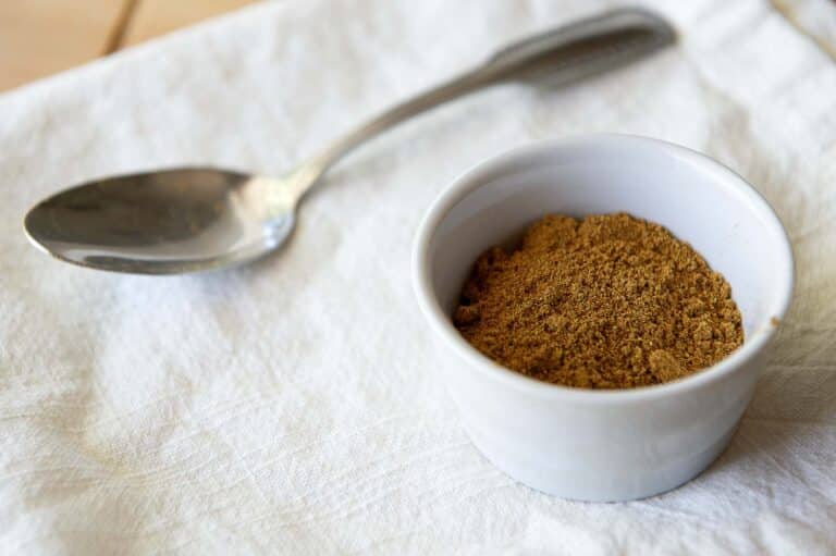 Advieh in a ramakin on a white linen, with a spoon beside it.