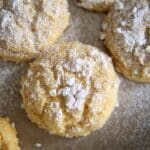 Close-up of Pumpkin Gooey Butter Cookies topped with a generous dusting of powdered sugar, arranged on a baking tray. The cookies have a golden, crumbly texture and are lightly covered in sugar.
