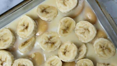 Close-up of a No Bake Banana Pudding Recipe featuring sliced bananas and vanilla wafer cookies covered in creamy pudding in a baking dish.