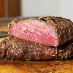 Smoked tri tip cut in half and sitting on a wooden cutting board.