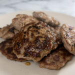 A pile of cooked sausage patties on a plate.