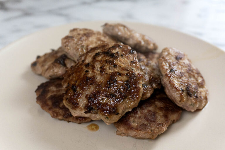A pile of cooked sausage patties on a plate.